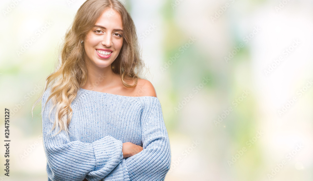 Beautiful young blonde woman wearing winter sweater over isolated background happy face smiling with crossed arms looking at the camera. Positive person.