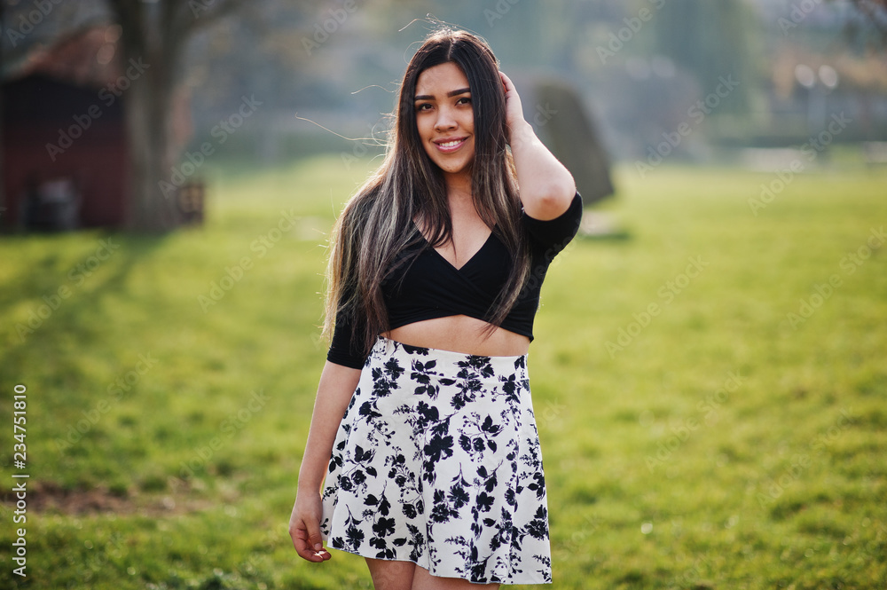 Fototapeta premium Pretty latino model girl from Ecuador wear on black tops and skirt posed at street.