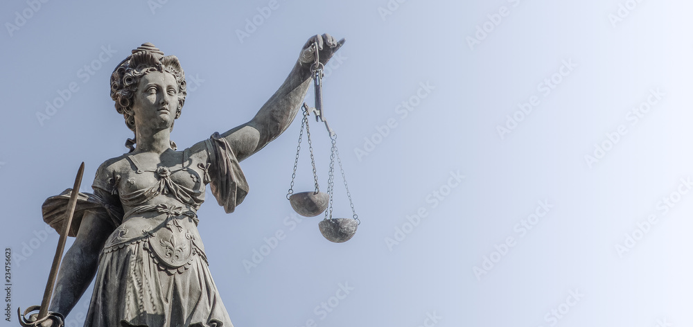 Statue a judge woman with scales and sword at smooth blue background in Frankfurt, Germany, details, closeup