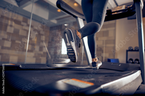 Close up of woman's legs running on treadmill. Gym interior.