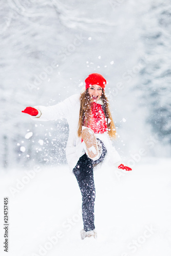 a girl in a winter jacket and warm accessories throw the snow an