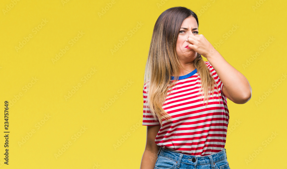 Young beautiful woman casual look over isolated background smelling something stinky and disgusting, intolerable smell, holding breath with fingers on nose. Bad smells concept.