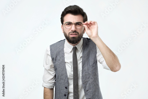 Funny good looking skeptical man in glasses looking at camera. He tries to make out the fine print on the contract. photo