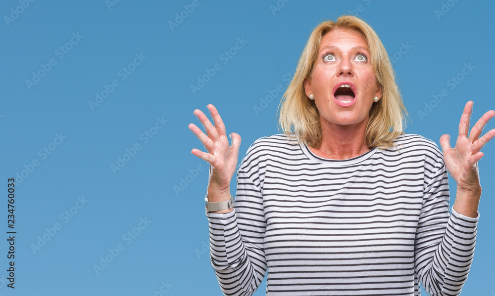 Fototapeta premium Middle age blonde woman over isolated background crazy and mad shouting and yelling with aggressive expression and arms raised. Frustration concept.