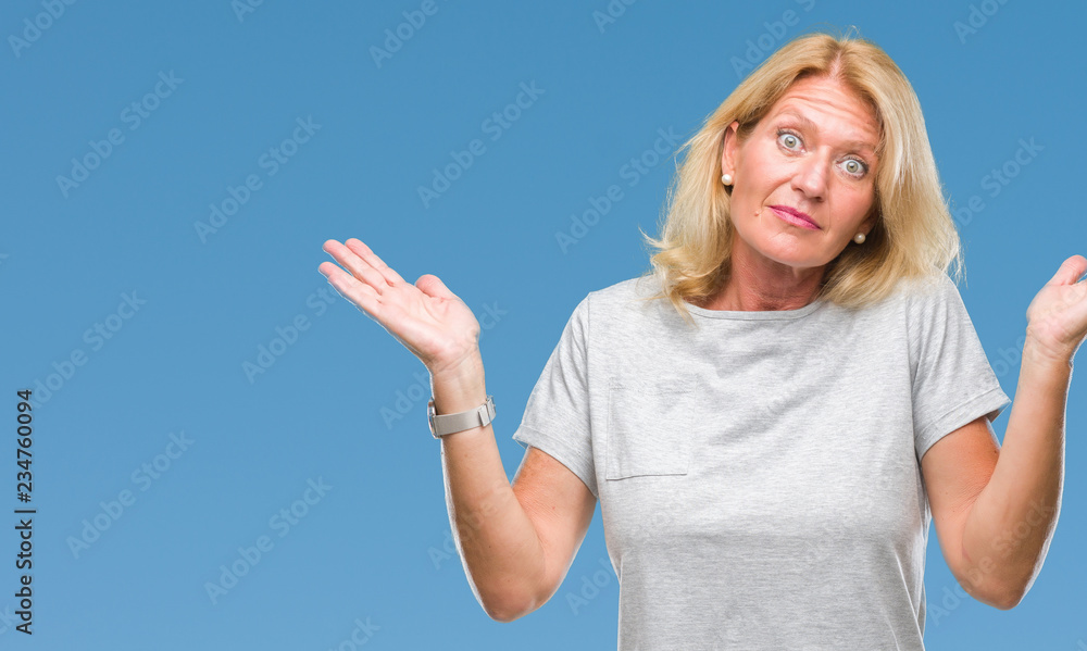 Middle age blonde woman over isolated background clueless and confused expression with arms and hands raised. Doubt concept. Middle age blonde woman over isolated background clueless and confused expression with arms and hands raised. Doubt concept.