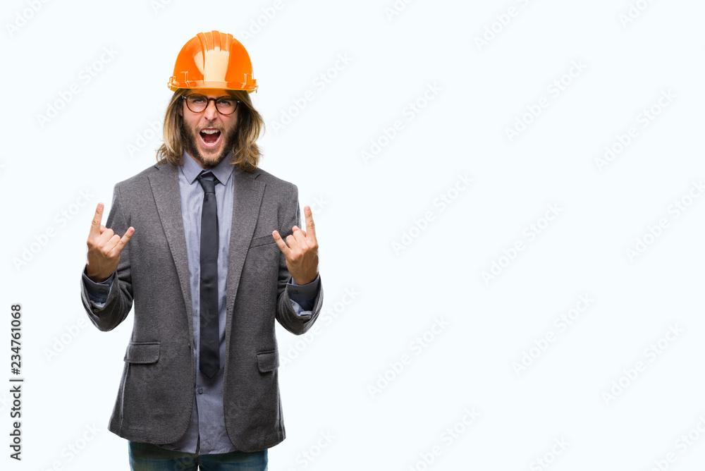 Young handsome architec man with long hair wearing safety helmet over isolated background shouting with crazy expression doing rock symbol with hands up. Music star. Heavy concept. Young handsome architec man with long hair wearing safety helmet over isolated background shouting with crazy expression doing rock symbol with hands up. Music star. Heavy concept.