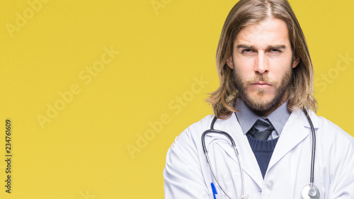 Young handsome doctor man with long hair over isolated background skeptic and nervous  disapproving expression on face with crossed arms. Negative person.