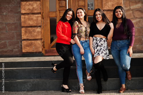 Group of four happy and pretty latino girls from Ecuador posed at street.