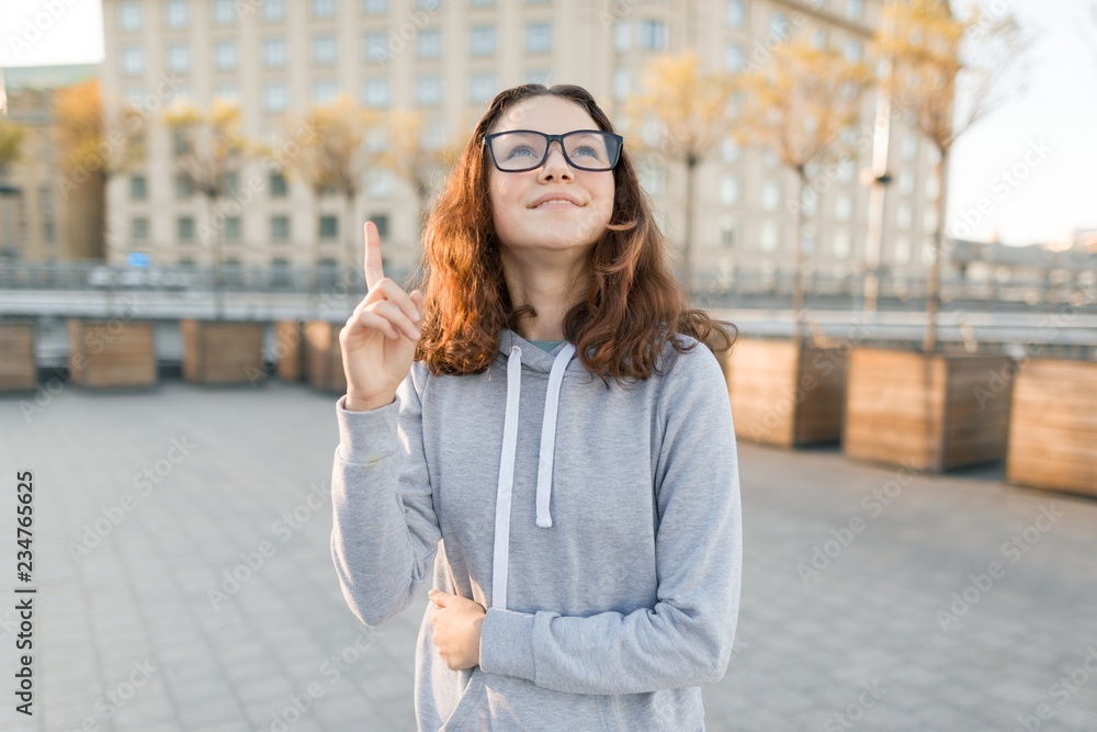 Outdoor portrait of smart teenager girl with glasses showing index finger up idea, eureka, golden hour. Outdoor portrait of smart teenager girl with glasses showing index finger up idea, eureka, golden hour.