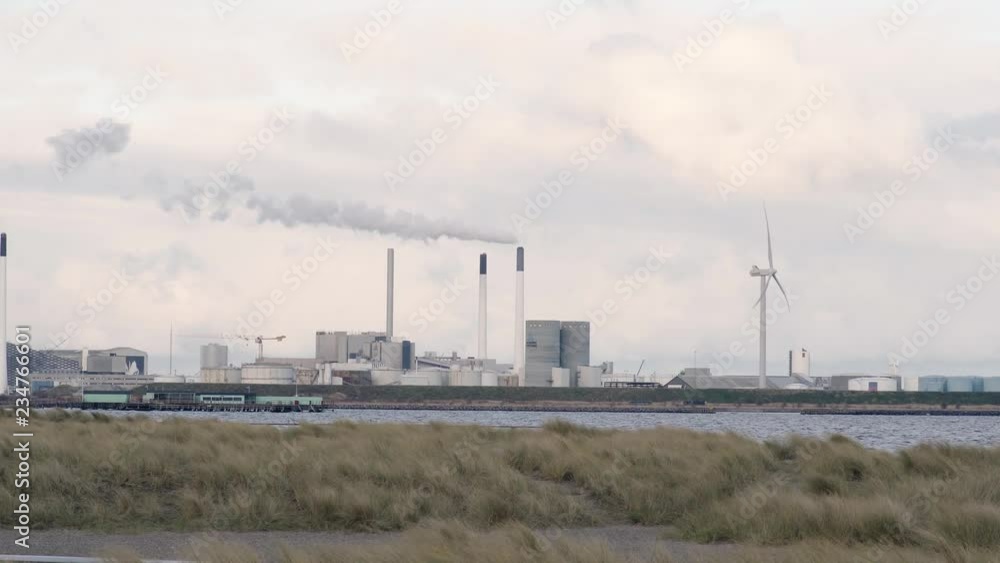 wind turbine beside a powerplant on amager beach denmark. windmill. green energy wind energy wind turbine beside a powerplant on amager beach denmark. windmill. green energy wind energy