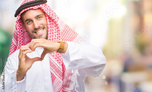 Young handsome man wearing keffiyeh over isolated background smiling in love showing heart symbol and shape with hands. Romantic concept.