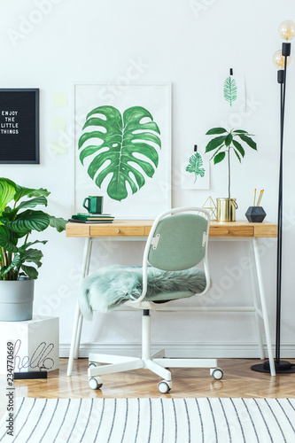 Stylish and modern scandinavian interior of home office desk with mock up poster frames  a lot of plants   office accessories and lamp. Modern composition of homeoffice desk.