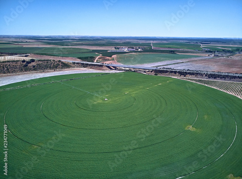 Aerial view of crop field with circular pivot irrigation sprinkler.