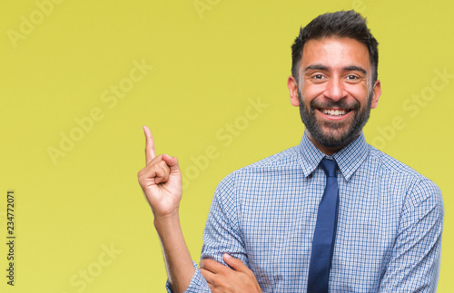Adult hispanic business man over isolated background with a big smile on face, pointing with hand and finger to the side looking at the camera.