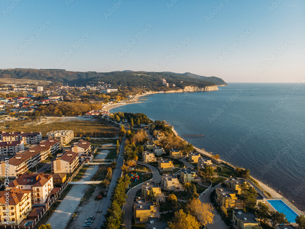 Sea coast with buildings on shore of beach, aerial panoramic view of ocean resort
