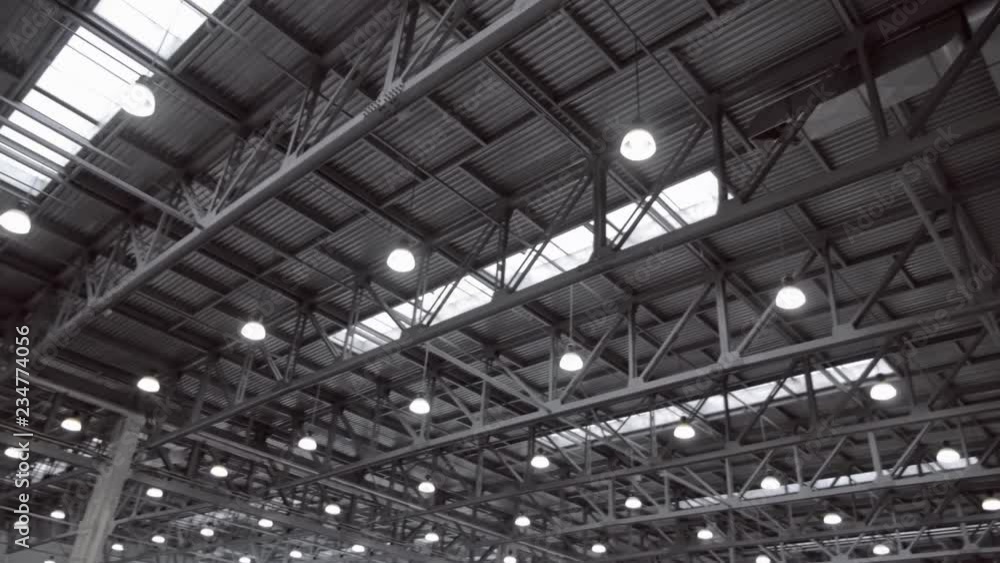 Hangar ceiling with many structural beams, ventilation pipes and luminous lamps. Shot in motion
Hangar ceiling with many structural beams, ventilation pipes and luminous lamps. Shot in motion