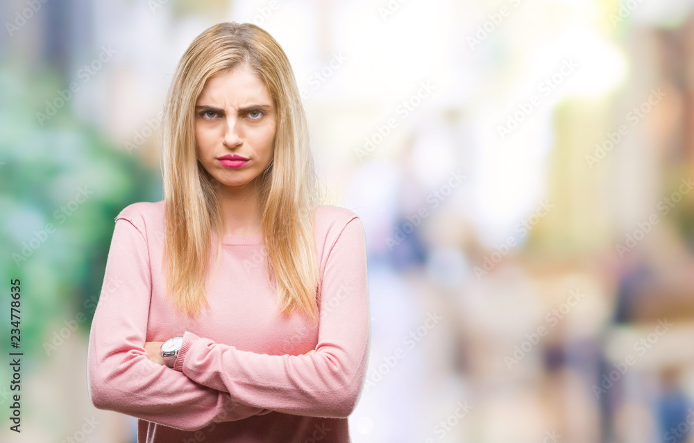 Young beautiful blonde woman wearing pink winter sweater over isolated background skeptic and nervous, disapproving expression on face with crossed arms. Negative person.