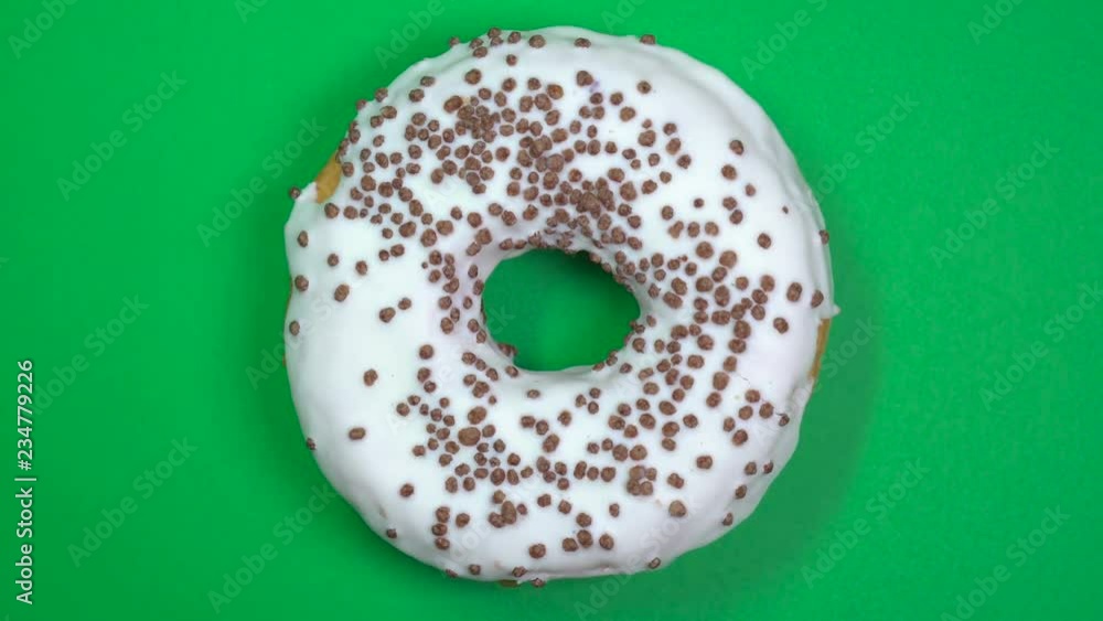 Tasty and fresh sprinkled donut close-up macro shot spinning on a green background. Tasty and fresh sprinkled donut close-up macro shot spinning on a green background.