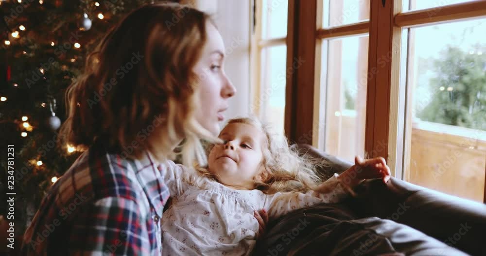 Mother and Daughter Having Fun on Christmas Morning. SLOW MOTION. Precious family moment, young mom playing with her toddler daughter by the window, winter landscape. Mother and Daughter Having Fun on Christmas Morning. SLOW MOTION. Precious family moment, young mom playing with her toddler daughter by the window, winter landscape.