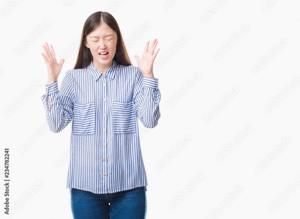 Young Chinese woman over isolated background celebrating mad and crazy for success with arms raised and closed eyes screaming excited. Winner concept Young Chinese woman over isolated background celebrating mad and crazy for success with arms raised and closed eyes screaming excited. Winner concept