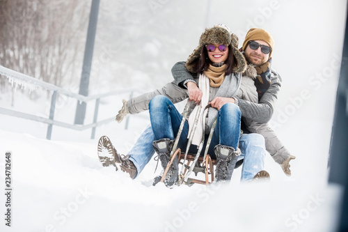 Young couple on sledge in winter outdoors