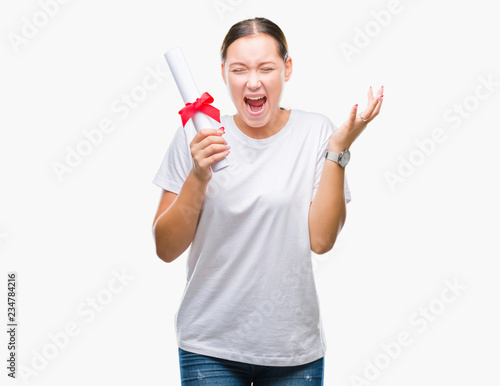 Young caucasian woman holding degree over isolated background very happy and excited, winner expression celebrating victory screaming with big smile and raised hands