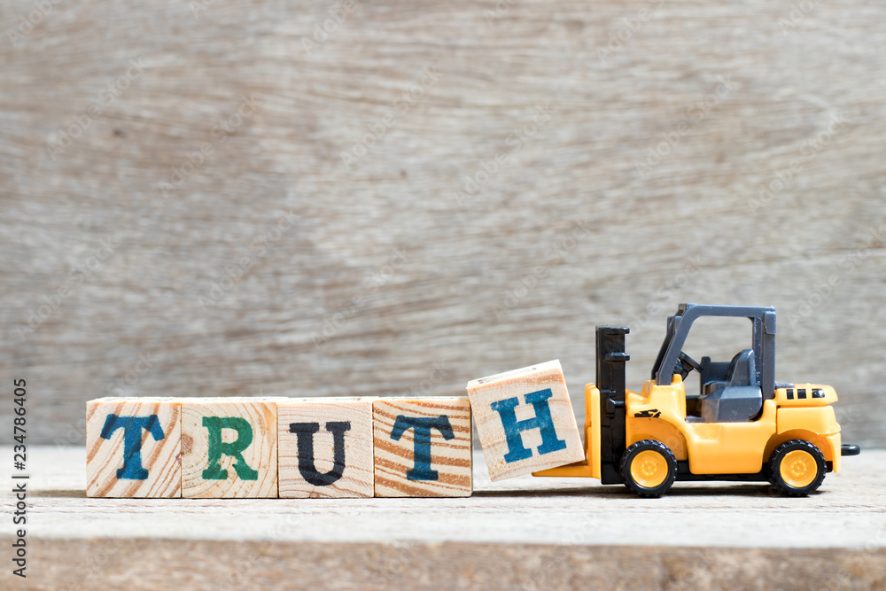 Fototapeta premium Toy forklift hold letter block h to complete word truth on wood background