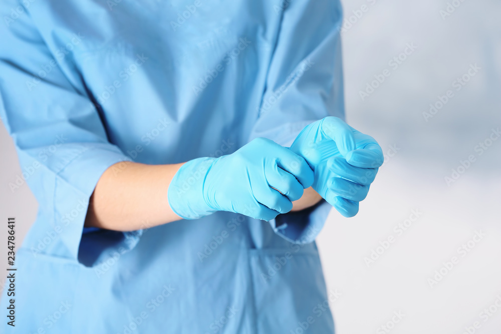 Obraz premium Doctor taking off medical gloves on color background