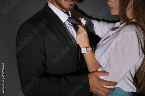 Woman molesting her male colleague on dark background, closeup. Sexual harassment at work © New Africa