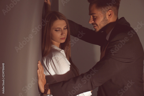 Boss molesting his female secretary on dark background. Sexual harassment at work