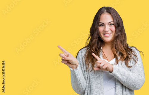 Beautiful plus size young woman wearing winter jacket over isolated background smiling and looking at the camera pointing with two hands and fingers to the side.