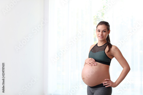 Young pregnant woman in fitness clothes at home. Space for text Free Download Young pregnant woman in fitness clothes at home. Space for text - GFXLoad