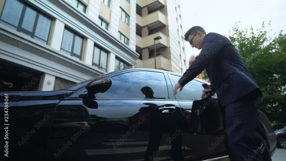 Anxious businessman getting in car talking on phone, problems with deal, startup Anxious businessman getting in car talking on phone, problems with deal, startup