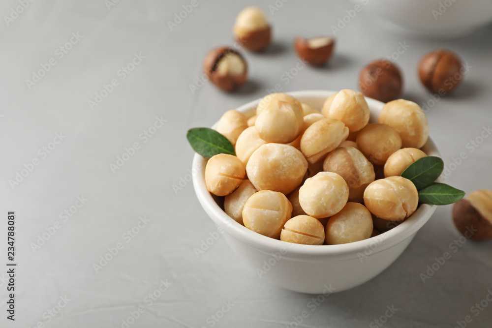 Bowl with shelled organic Macadamia nuts and space for text on grey background Bowl with shelled organic Macadamia nuts and space for text on grey background