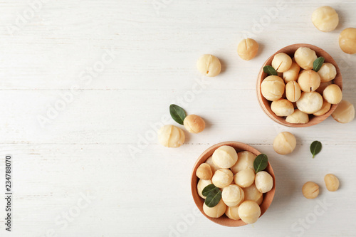 Bowls with shelled organic Macadamia nuts and space for text on white table, top view