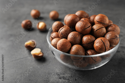 Bowl with organic Macadamia nuts and space for text on grey background