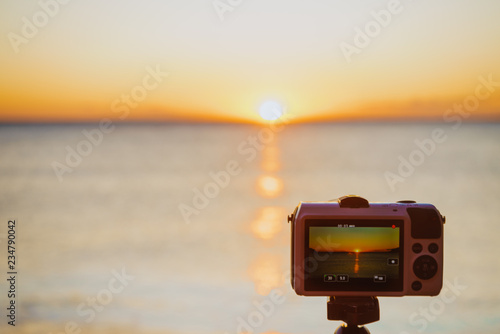 Camera taking picture film of sunrise over sea surface