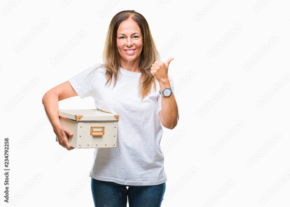 Middle age hispanic woman moving holding packing box over isolated background happy with big smile doing ok sign, thumb up with fingers, excellent sign Middle age hispanic woman moving holding packing box over isolated background happy with big smile doing ok sign, thumb up with fingers, excellent sign