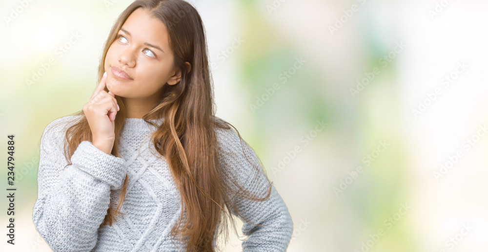 Young beautiful brunette woman wearing sweater over isolated background with hand on chin thinking about question, pensive expression. Smiling with thoughtful face. Doubt concept.