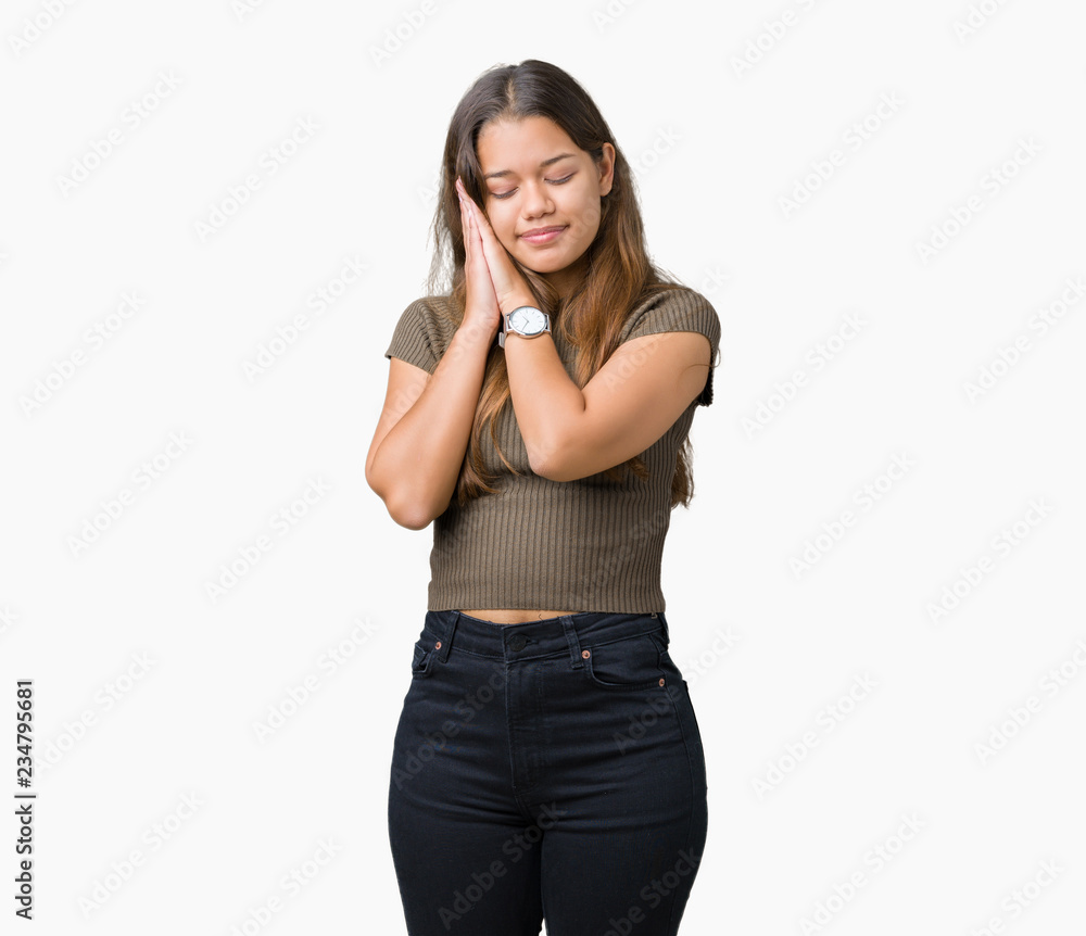 Young beautiful brunette woman over isolated background sleeping tired dreaming and posing with hands together while smiling with closed eyes. Young beautiful brunette woman over isolated background sleeping tired dreaming and posing with hands together while smiling with closed eyes.