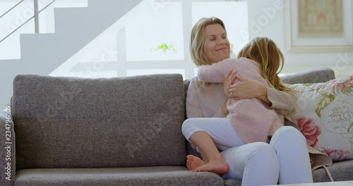 Mother embracing her daughter in living room 4k photo