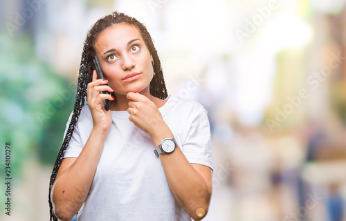 Young braided hair african american girl showing calling using smartphone over isolated background serious face thinking about question, very confused idea