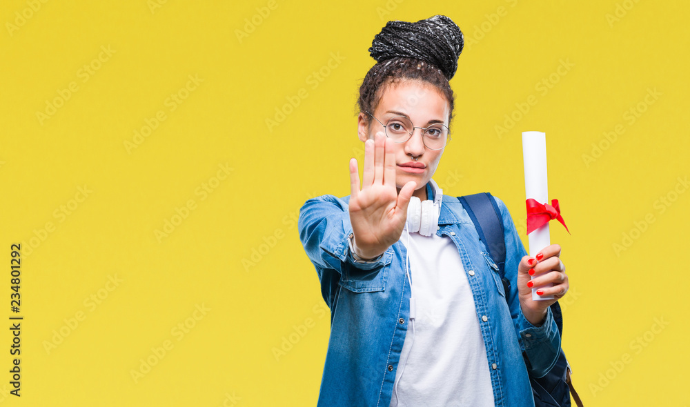 Young braided hair african american student girl holding degree over isolated background with open hand doing stop sign with serious and confident expression, defense gesture Young braided hair african american student girl holding degree over isolated background with open hand doing stop sign with serious and confident expression, defense gesture