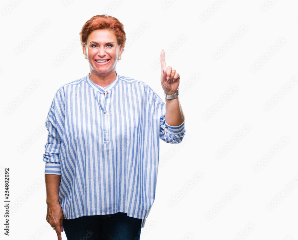 Naklejka premium Atrractive senior caucasian redhead woman over isolated background showing and pointing up with finger number one while smiling confident and happy.