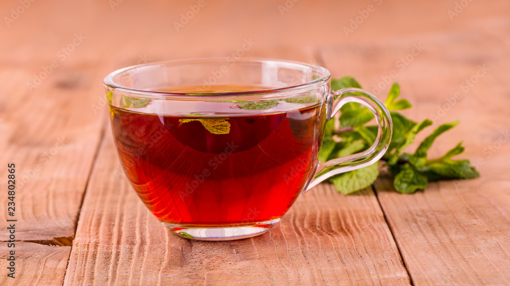 The tea cup with mint on old wooden background. The tea cup with mint on old wooden background.