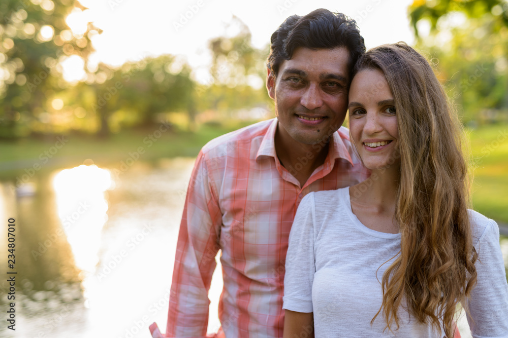 Naklejka premium Close up of happy multi ethnic couple smiling and in love agains