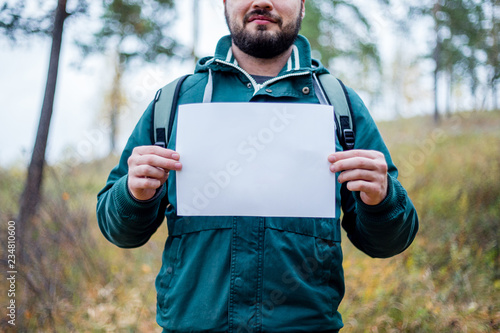 Fotografía male hiker is holding a white paper where you can insert your text