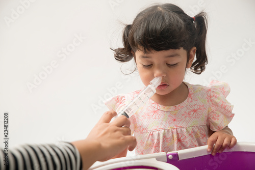 Asian mother making nasal wash for her baby girl by flushing kid'nose with syringe and saline. An Irrigation can benefit people who have sinus problems,nasal allergies isolated on white background