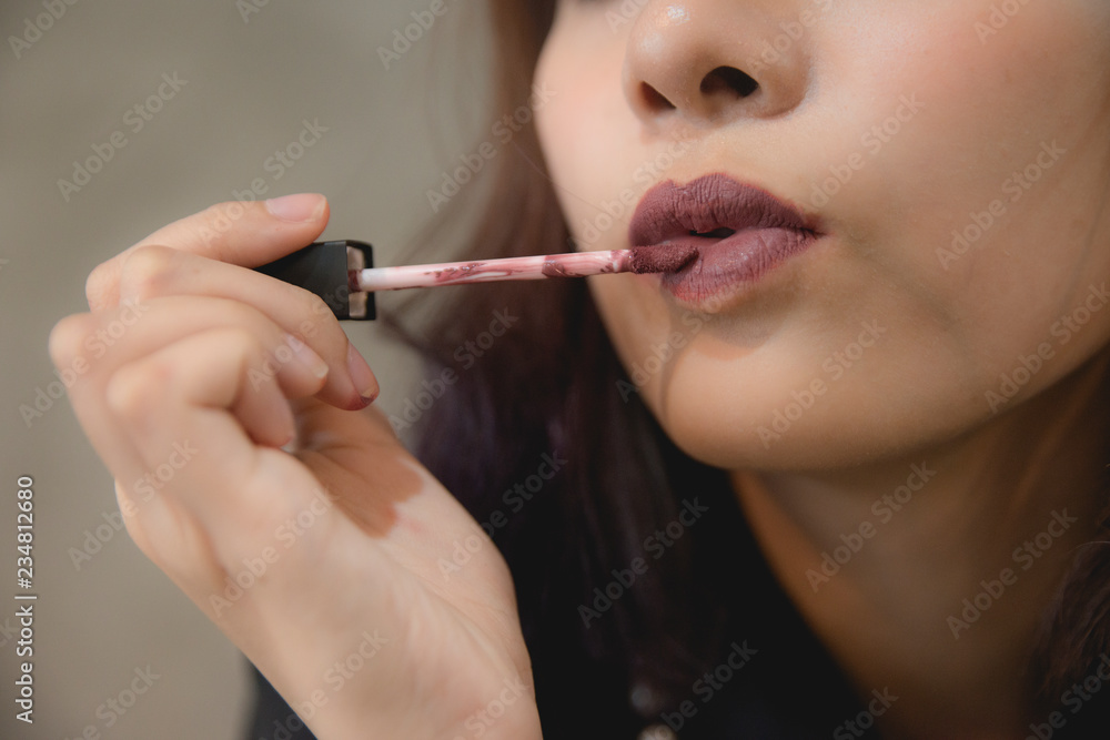 portrait of teenage Asian girl applying lipstick and put lipstick on her lips.Fashion Makeup Concept isolate on gray background portrait of teenage Asian girl applying lipstick and put lipstick on her lips.Fashion Makeup Concept isolate on gray background