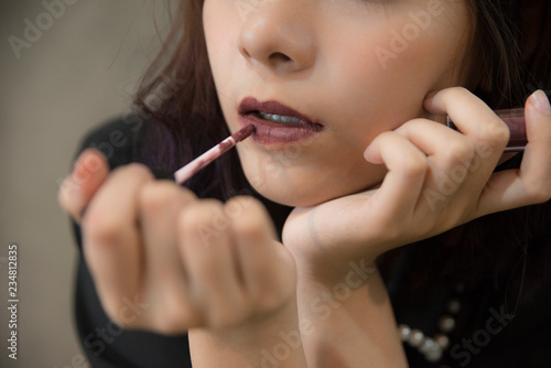 portrait of teenage Asian girl applying lipstick and put lipstick on her lips.Fashion Makeup Concept isolate on gray background